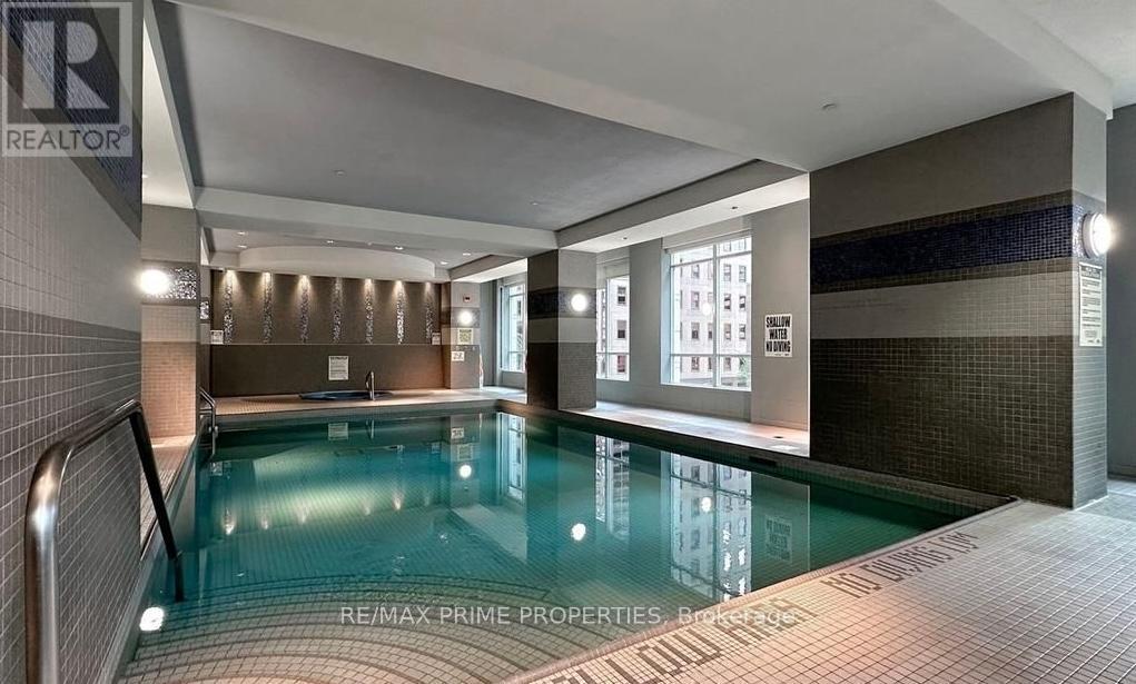 A swimming pool inside a building with a tiled wall.
