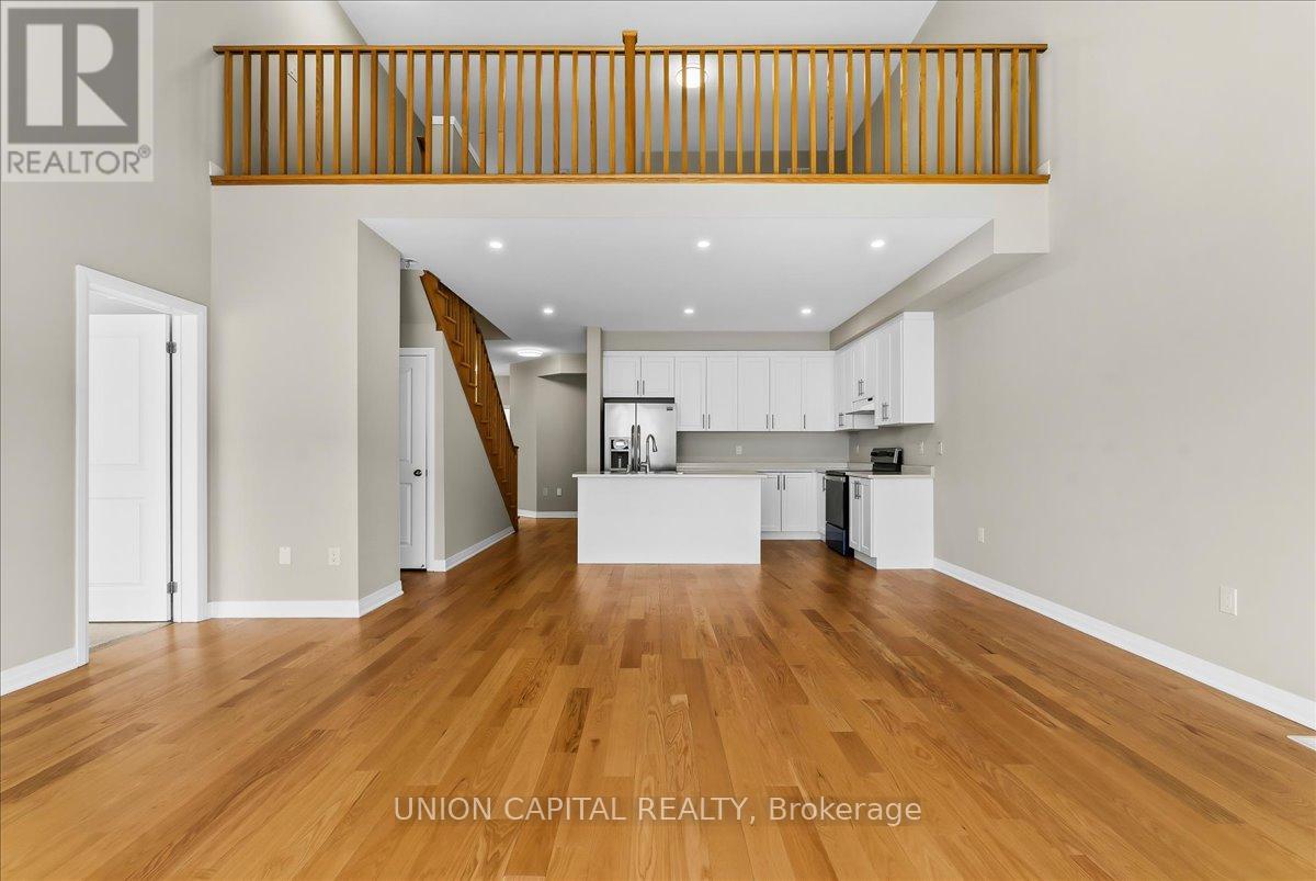 A spacious living room with wood flooring and a staircase with wooden railings.
