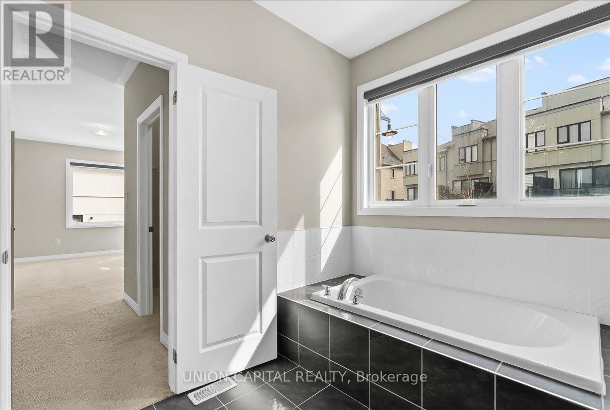 A bathroom with a tub and a window showing a view of buildings outside.