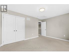 A bedroom with a white closet and carpeted floor.