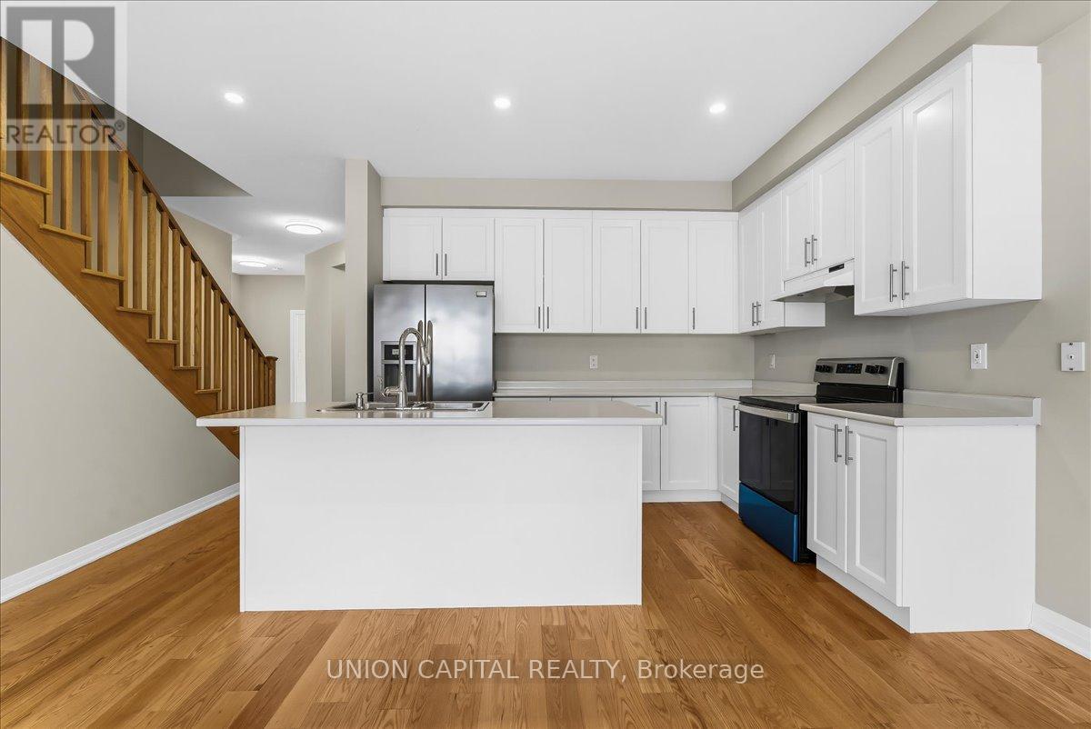 A modern kitchen with white cabinets and a wooden staircase.