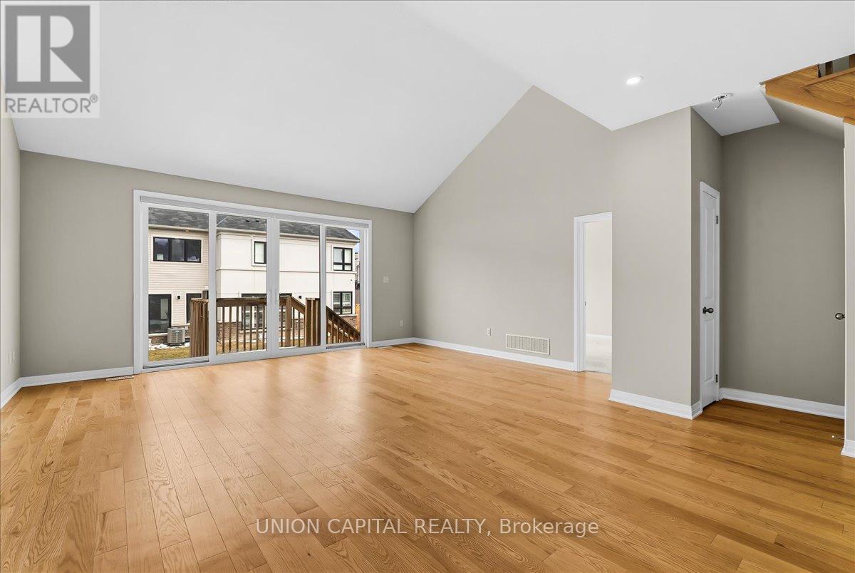 A spacious room with wooden flooring and a large window.