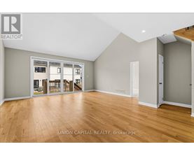 A spacious room with wooden flooring and a large window.