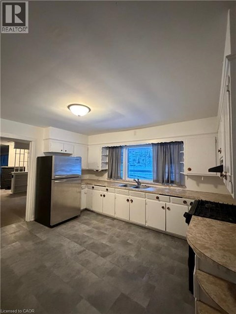 A kitchen with white cabinets and a black fridge.