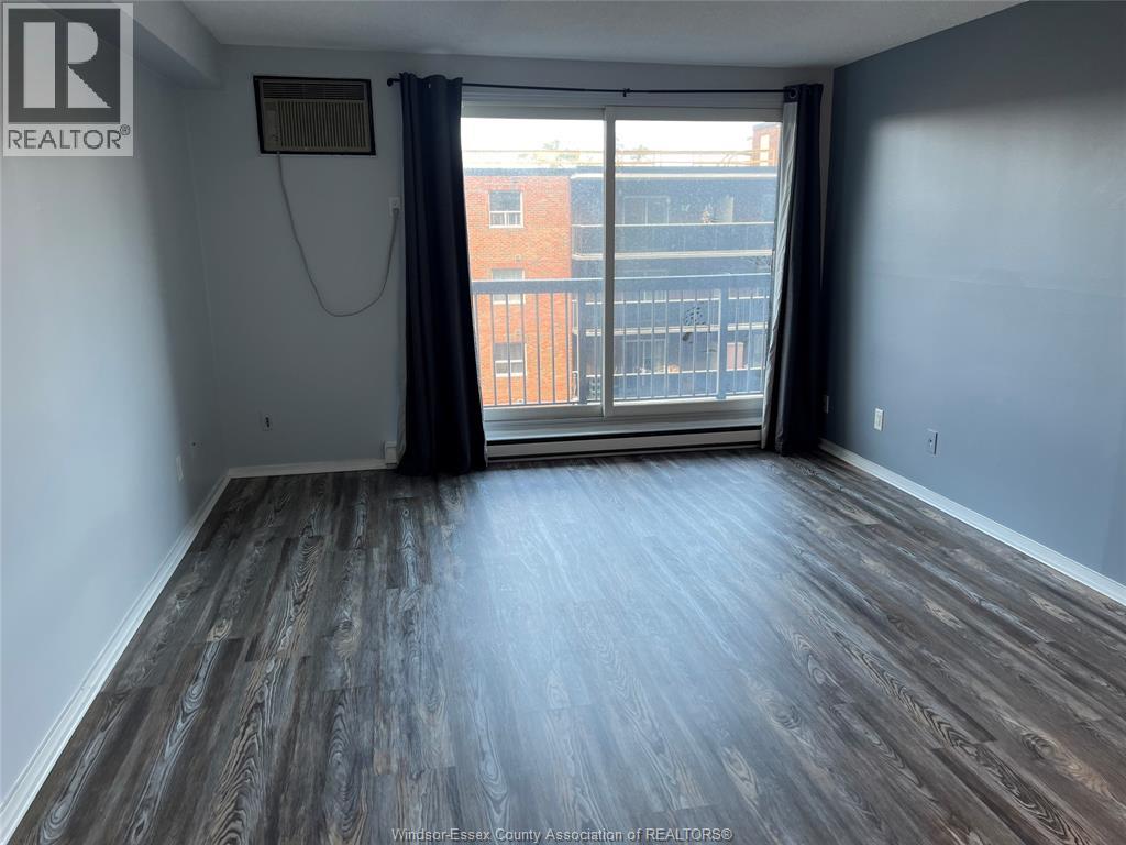 A room with wooden flooring and a sliding glass door leading to a balcony.