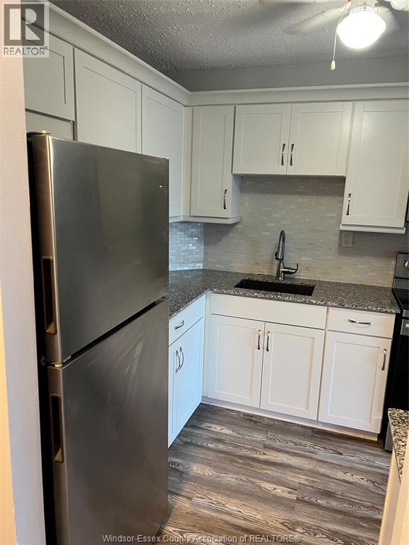 A kitchen with a black fridge and white cabinets.