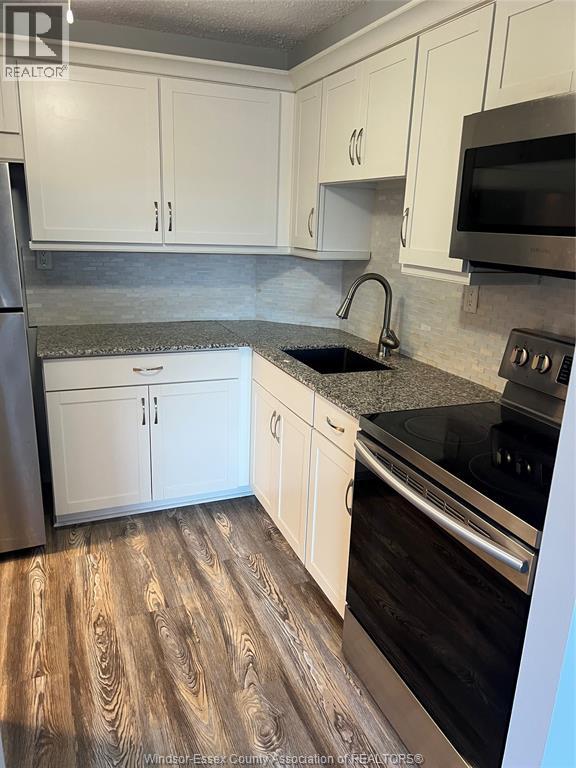 A kitchen with white cabinets and a black stove top oven.