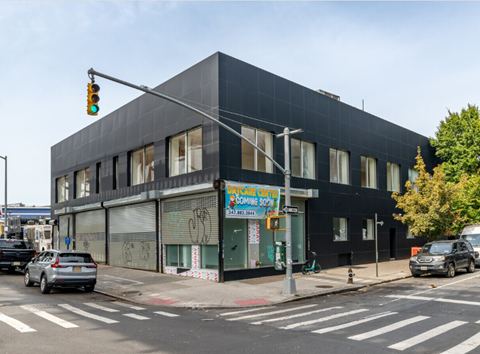 A black building with a sign that says "Coming Soon" is on the corner of a street.
