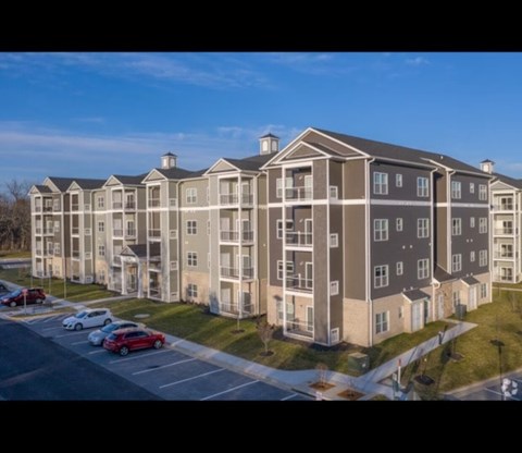 A large apartment complex with a parking lot in front.