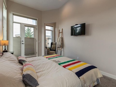 A bedroom with a large bed and a flat screen TV mounted on the wall.