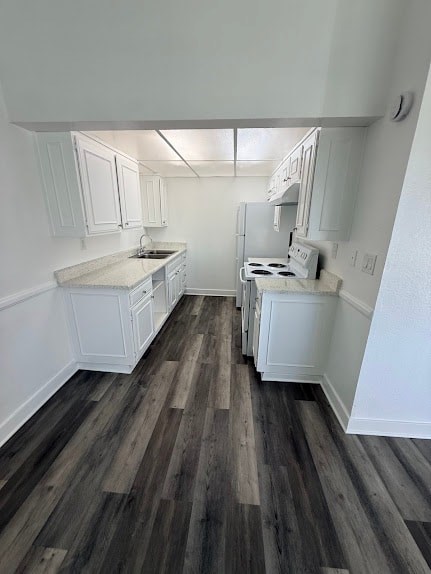 A kitchen with white cabinets and a wood floor.
