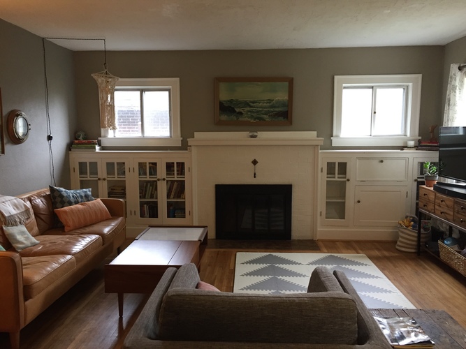 A living room with a fireplace and a brown couch.