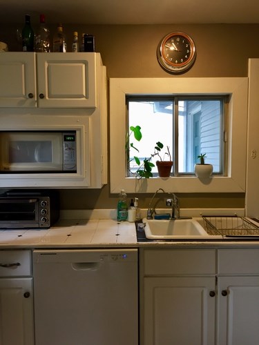 A kitchen with a white microwave, dishwasher, and sink.