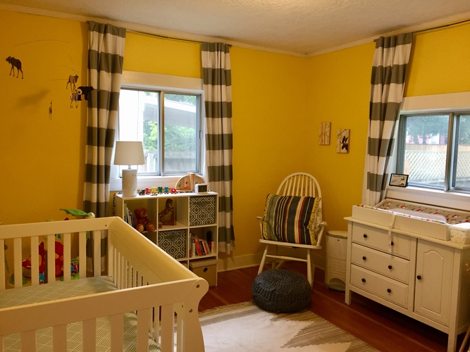 A baby room with a crib, a chair and a dresser.