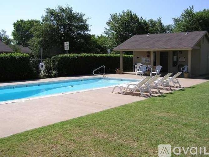 A pool with chairs and a building in the background.
