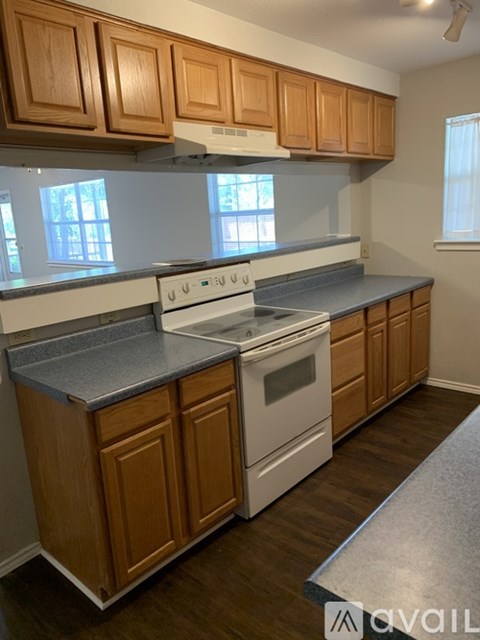 A kitchen with wooden cabinets and a white stove top oven.