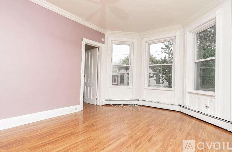 A room with pink walls and wooden floors is available for rent.