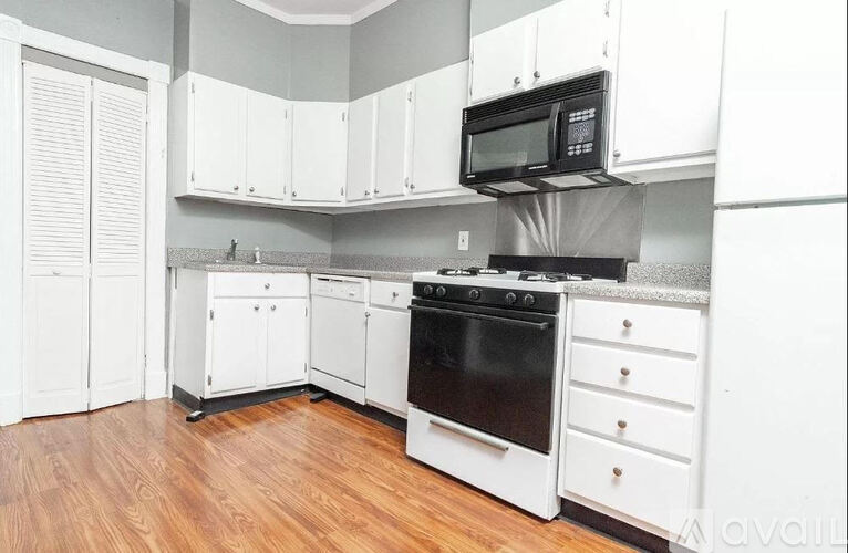 A kitchen with white cabinets and black appliances.
