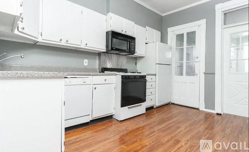 A kitchen with white cabinets and a black microwave.