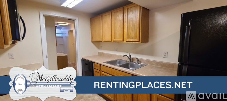 A kitchen with wooden cabinets and a black refrigerator is on the market.