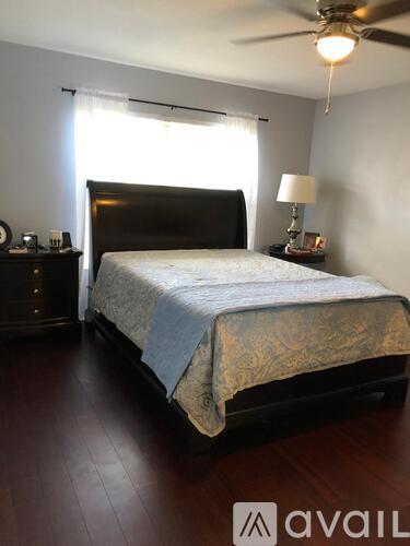 A bedroom with a large bed and a ceiling fan.