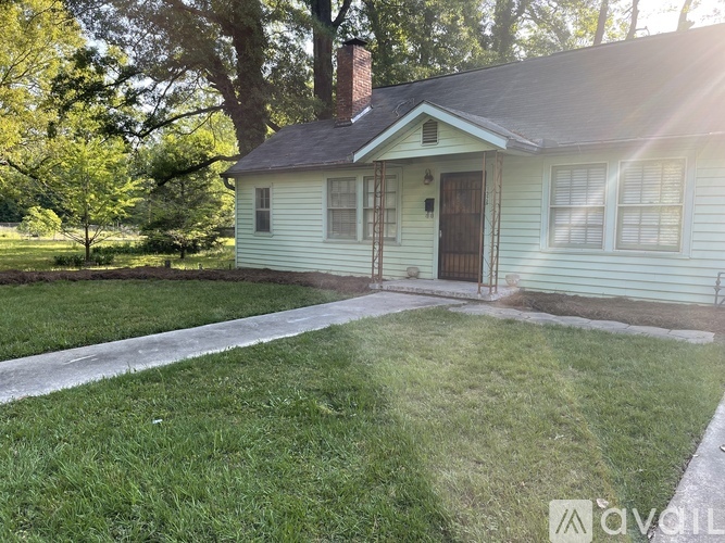 A small house with a porch and a tree in front.