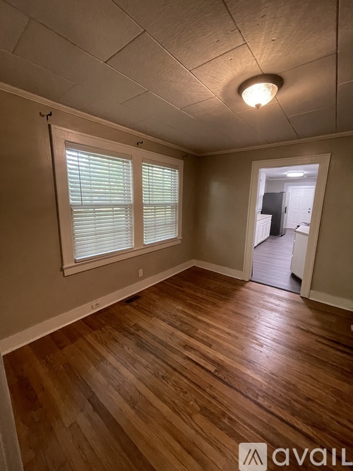 A room with wooden floors and a window with blinds.