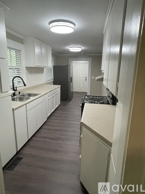A kitchen with white cabinets and a black refrigerator.