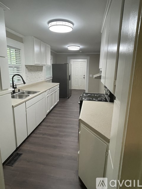 A kitchen with white cabinets and a black refrigerator.