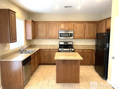A kitchen with wooden cabinets and a black refrigerator.