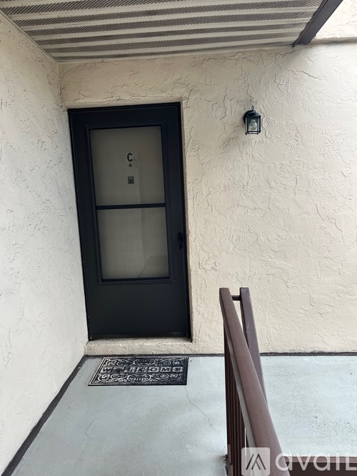 A black door with a glass window is set in a white wall.