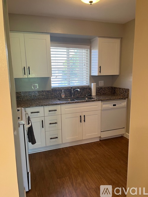 A kitchen with white cabinets and a granite countertop.