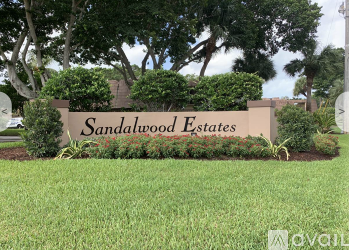 A sign that says "Sandalwood Estates" in front of some trees.