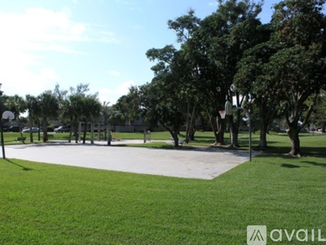 A park with a basketball court and trees.