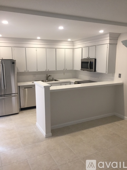 A kitchen with white cabinets and a white island.
