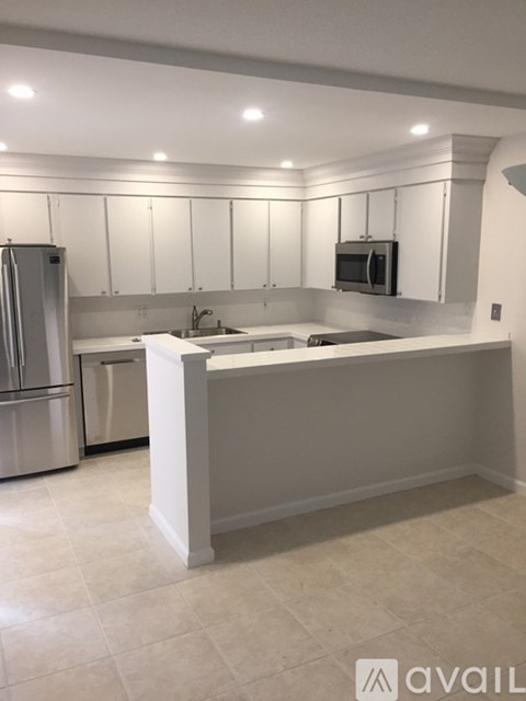 A kitchen with white cabinets and a white island.