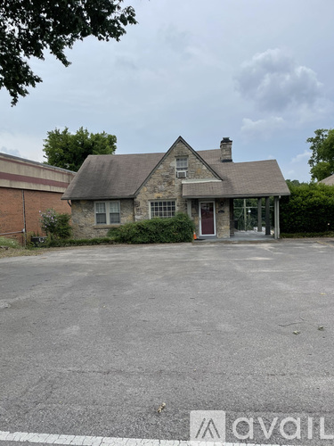 A house with a grey roof and a red door is surrounded by a parking lot.