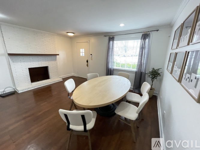 A dining room with a white fireplace and a wooden table.