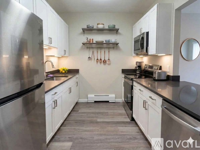 A kitchen with white cabinets and a stainless steel refrigerator.