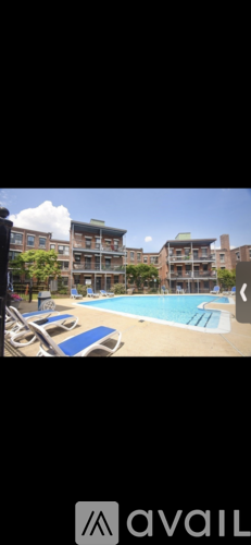 A swimming pool surrounded by sun loungers and buildings.