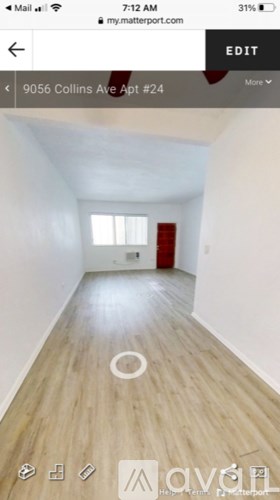 A white room with wooden flooring and a red door.