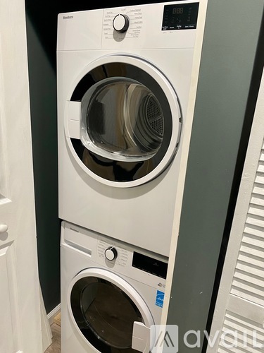 Two white front loading washing machines stacked on top of each other.