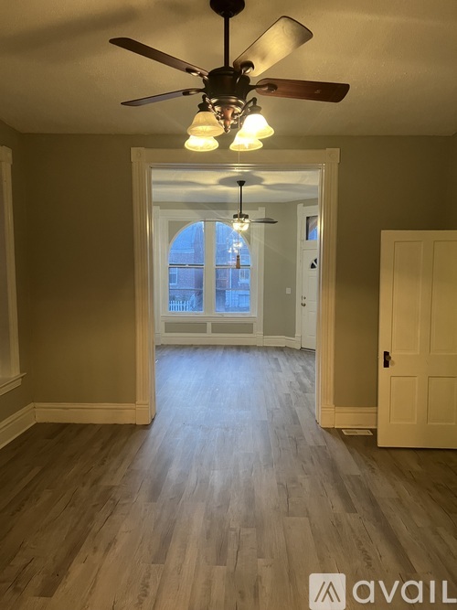 A room with a ceiling fan and a door leading to a balcony.