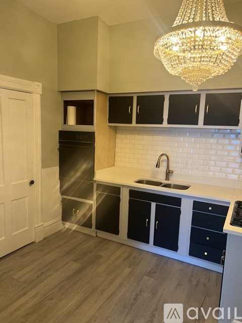 A kitchen with a white door, black cabinets, and a chandelier.