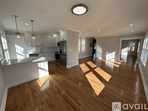 A spacious kitchen and living room with wooden flooring and modern lighting fixtures.