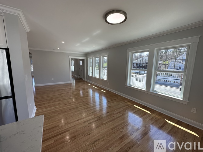 A spacious room with wooden floors and large windows.