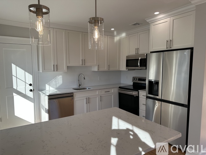 A kitchen with white cabinets and a marble countertop.