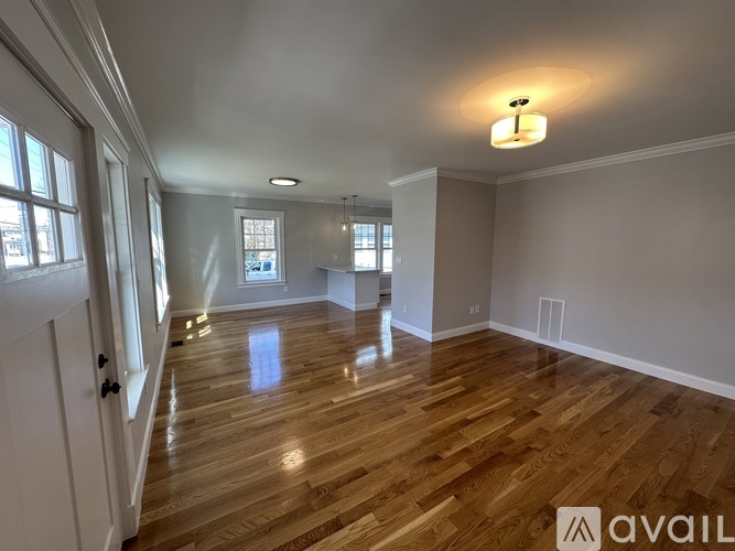 A spacious room with wooden flooring and a large window.
