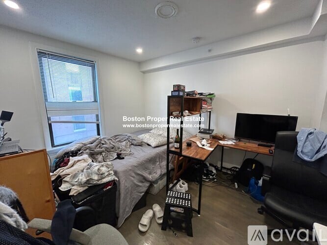 A messy bedroom with a bed, desk, and chair.