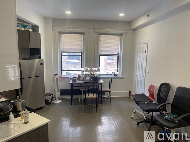 A kitchen with a refrigerator, a table with chairs, and a window.